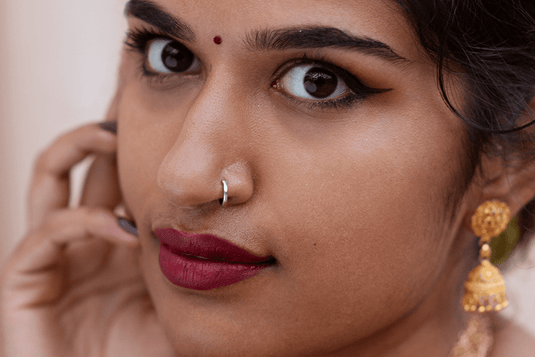 A trendy, vintage-look, minimalist, nose pin made with mixed metals such as silver and gold being worn by an Indian woman. 