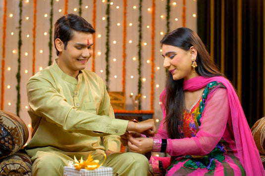 An Indian brother and sister celebrating the Indian festival of raksha bandhan by tying the sacred band of rakhi around the brother's wrist. 