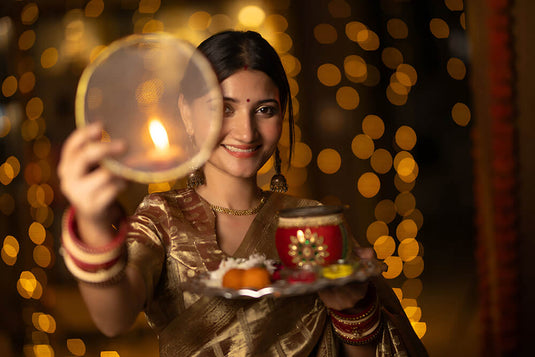 A woman celebrating karwa chauth with wearing gold jewelry, such as rings that are gifted to her.  