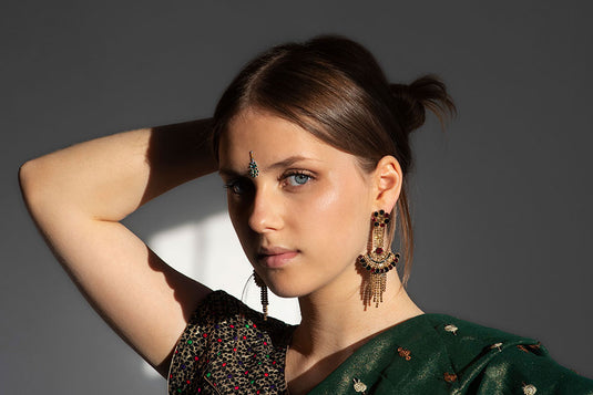 A woman wearing a traditional jhumka earring that is elevating her Indian saree look. With a collection of 10 best earrings that are perfect for her saree look.  